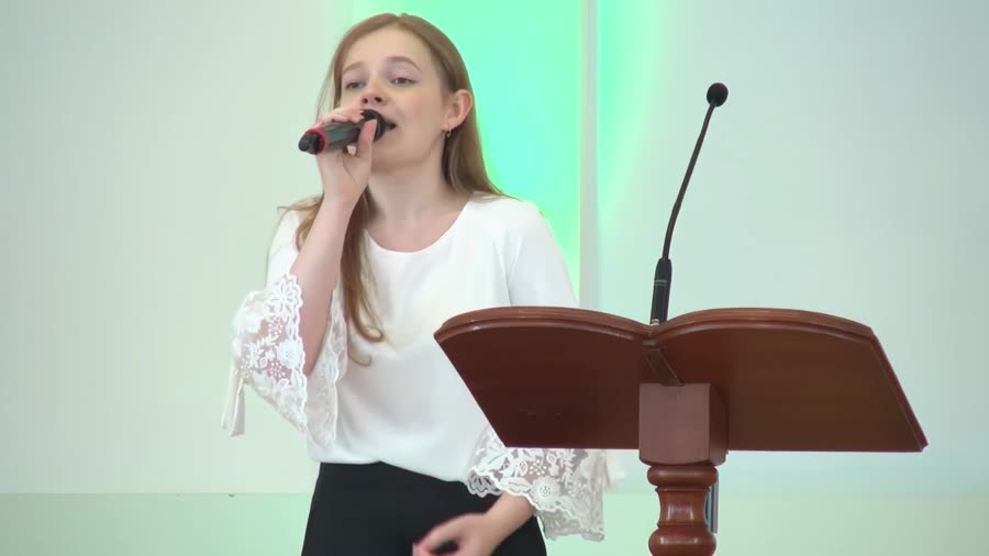 Певица с микрофоном у кафедры во время музыкального номера